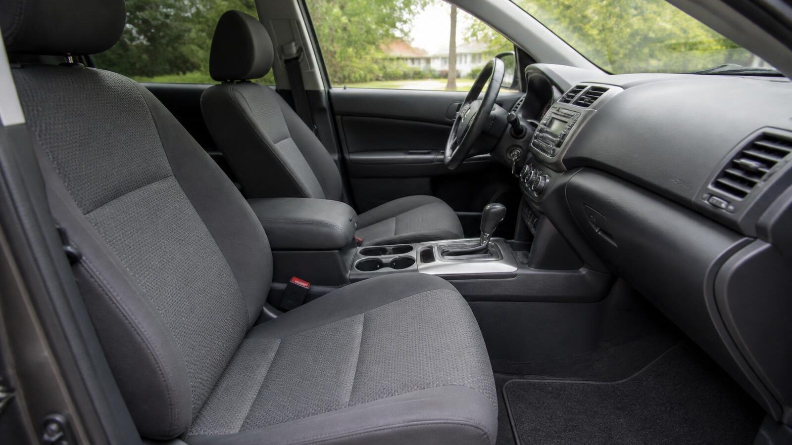 The clean interior of an everyday family SUV: wiped dashboard, tidy console, vacuumed cloth seats and clean floor mats.